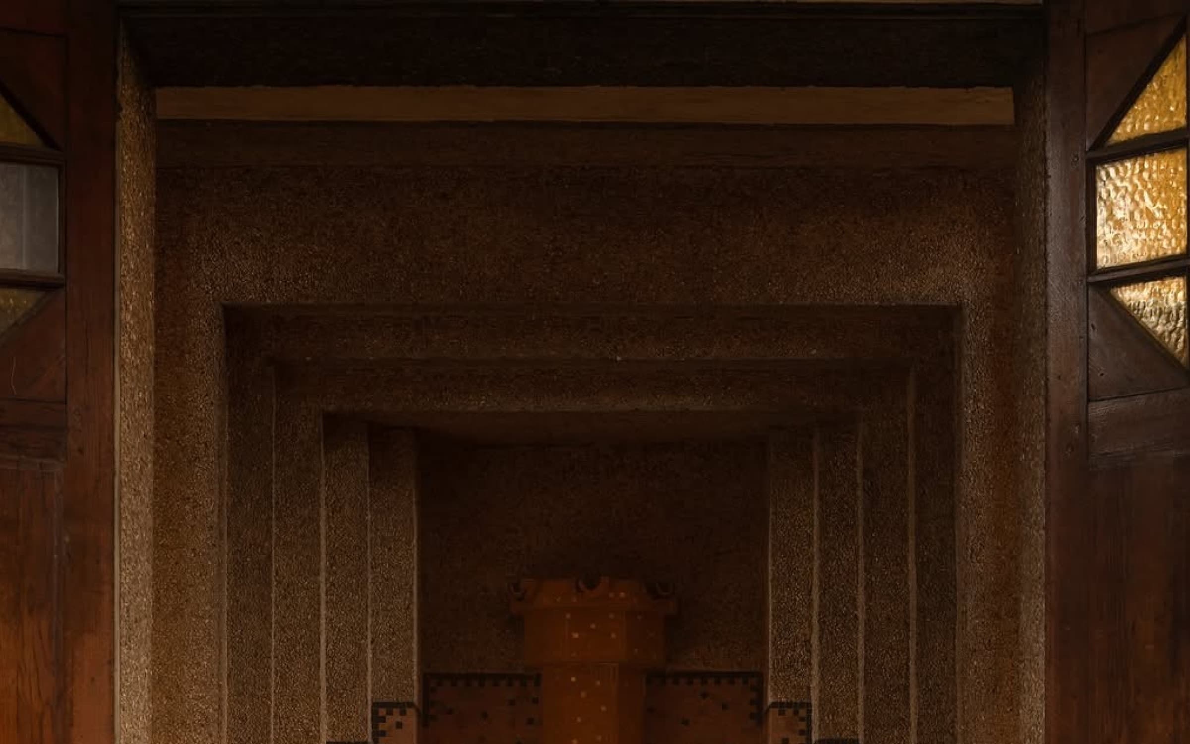 A warm brown wooden doorway with amber glass panes