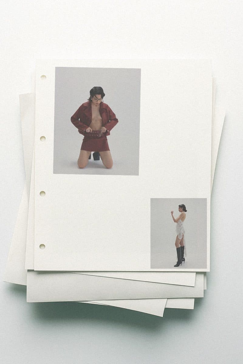 Loose sheets stacked on a white surface, holding small photographs of two models in an editorial layout.