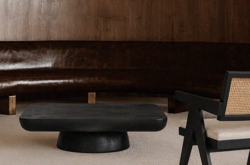 A curved, timber-lined room with a low black table and a black cane chair.