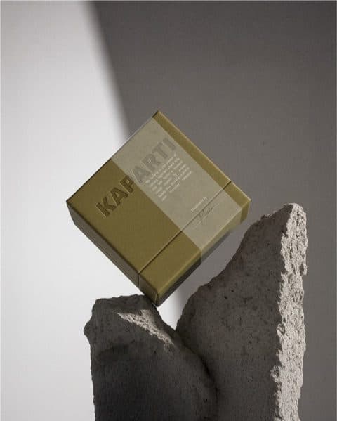 A khaki and cream Kaparti box balanced on two pieces of rough grey stone.