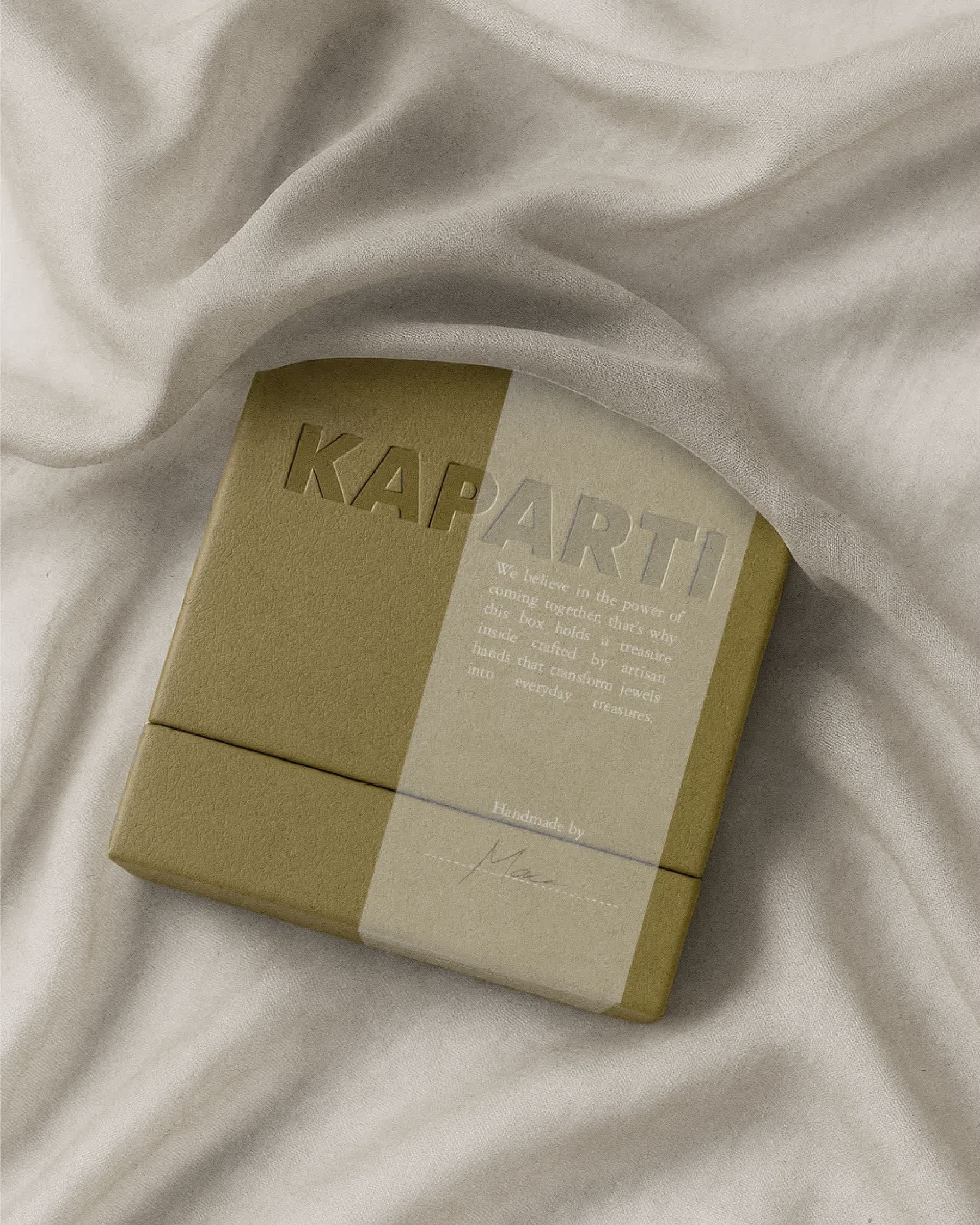 Creased cream fabric with the corner of a khaki Kaparti box below.