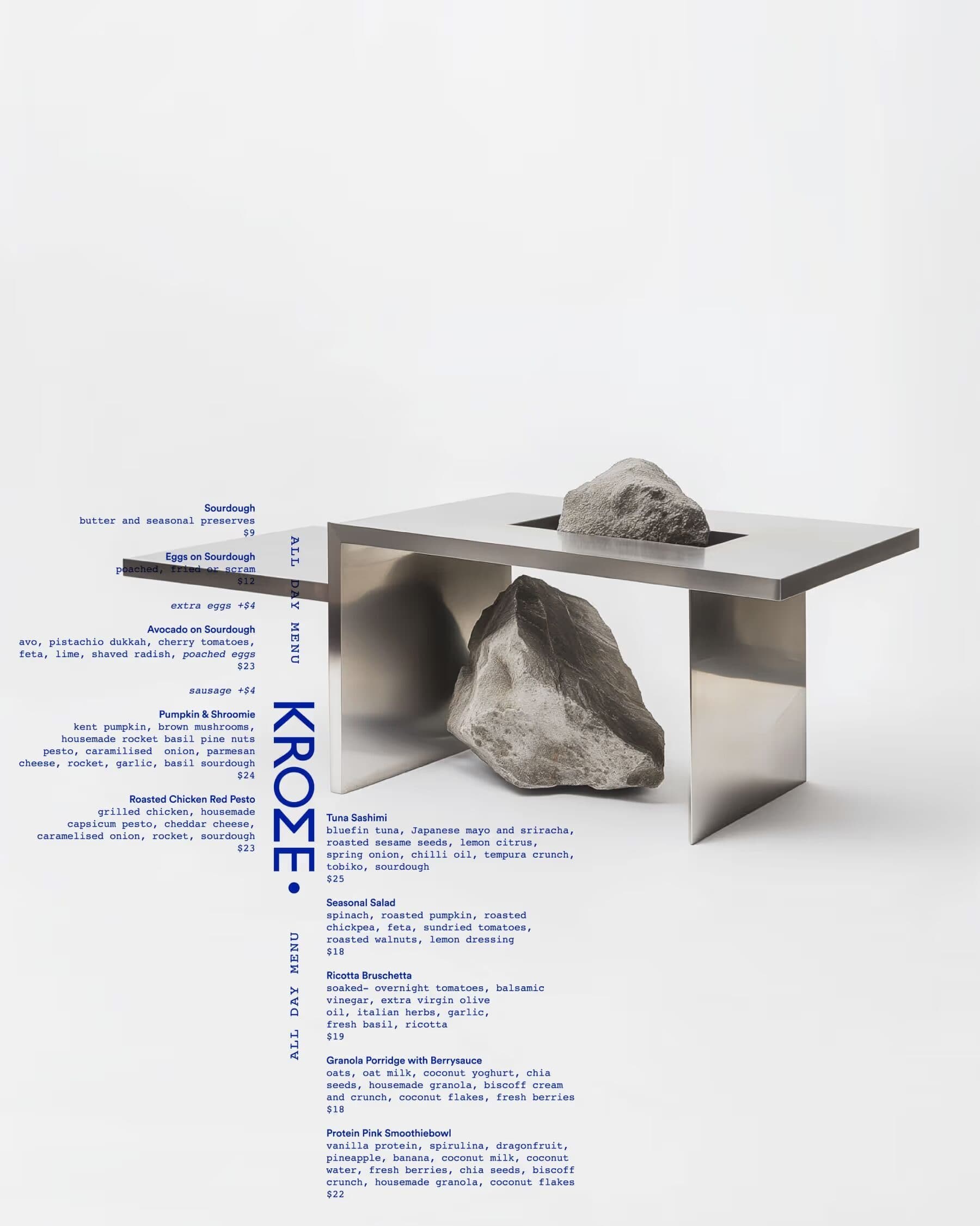A menu poster with small blue text and a vertical Krome wordmark beside a steel table holding a rock.