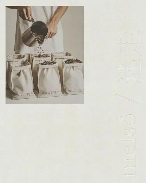 Hands pouring coffee beans from a steel scoop into a row of cream cloth bags, beside a faint 迷走 mark.
