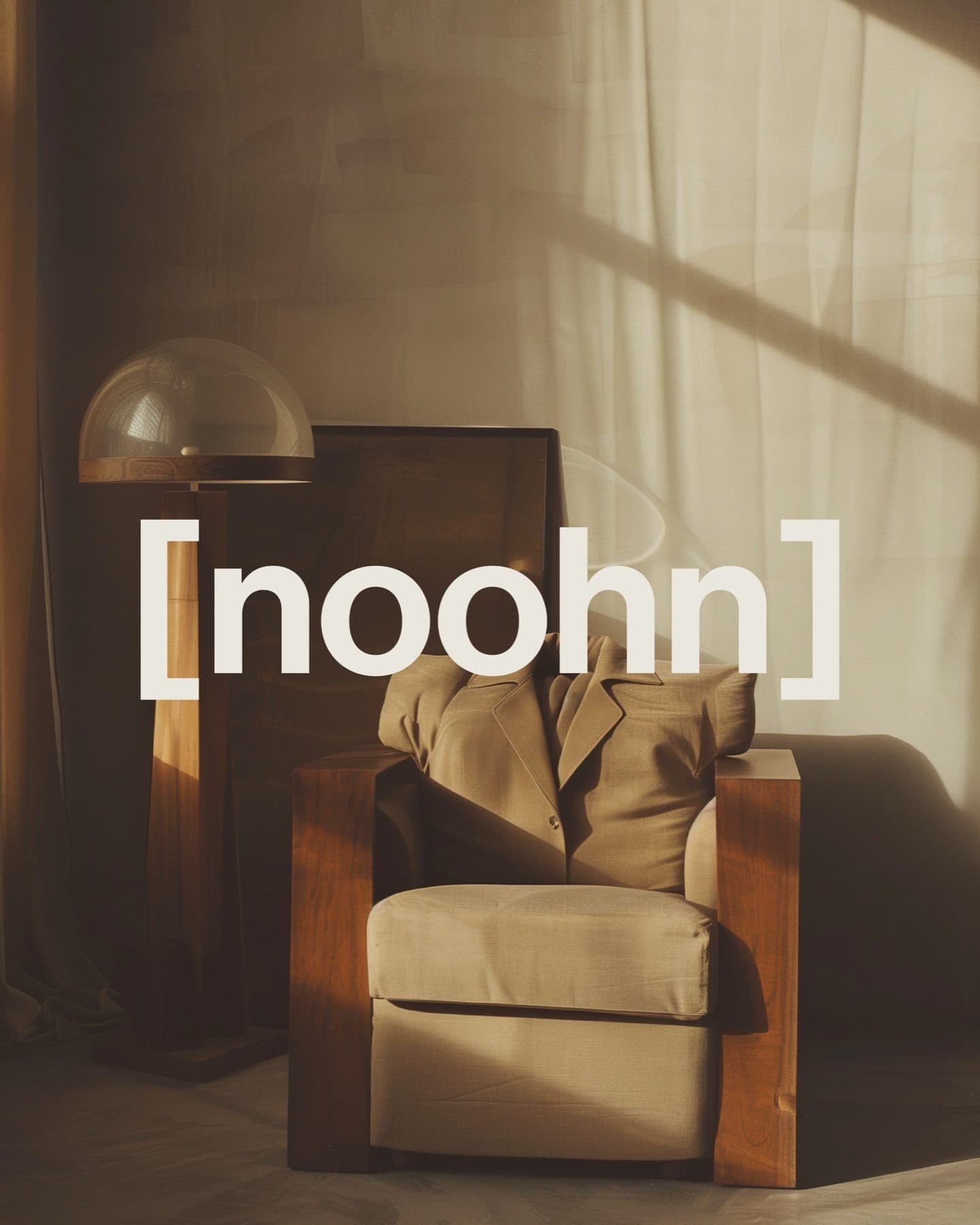 A cream armchair with a wooden frame beside a lamp in warm window light, with the noohn wordmark across the picture.