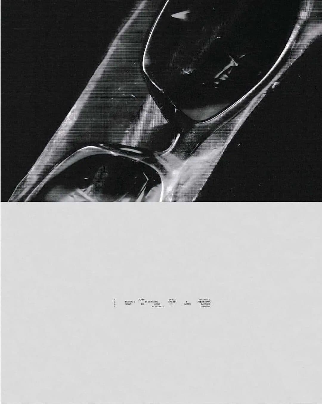 A black and white close-up of glasses on a textured surface, above a pale panel with small type.
