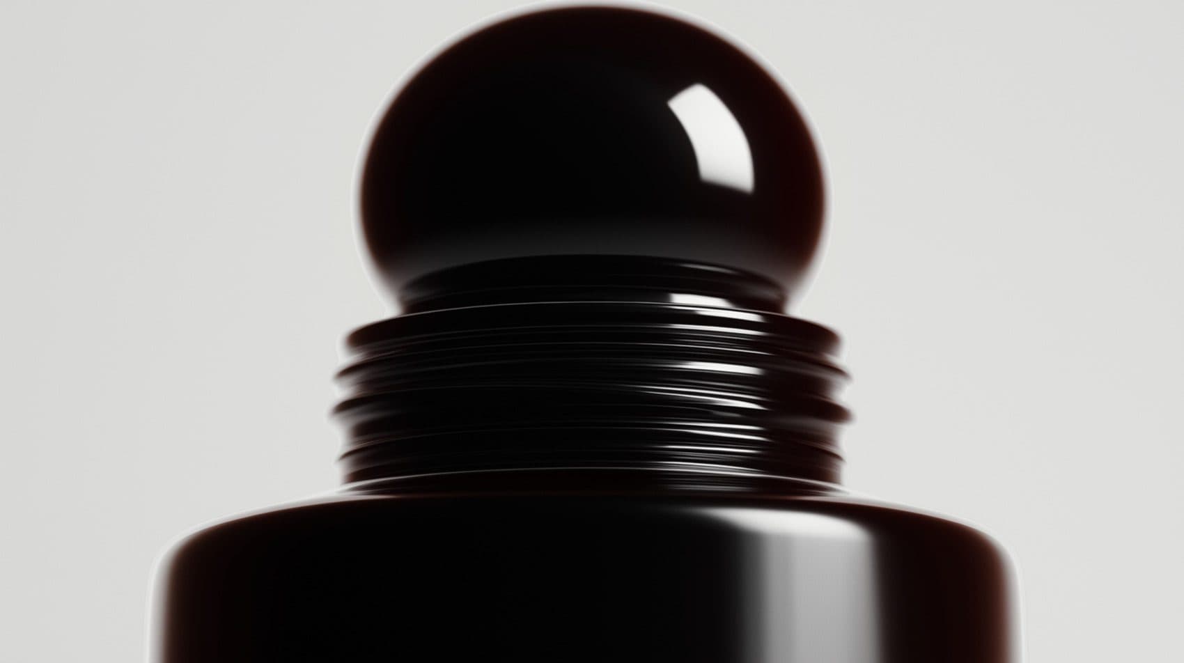 A glossy black bottle cap with ridged threads, seen close against a pale grey ground.