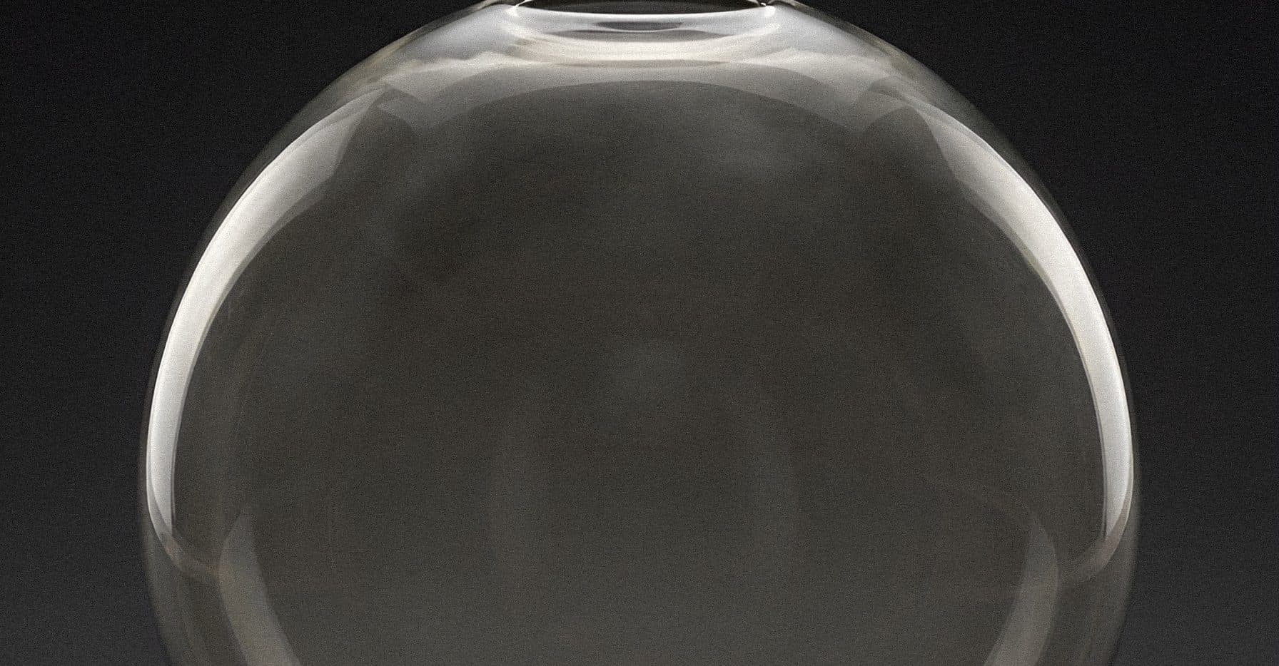 A clear glass sphere with a small open neck, lit against a black ground.