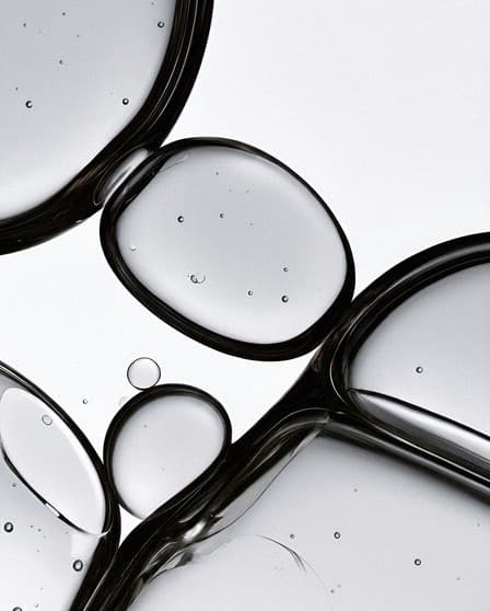 A macro of glass droplets and black metal rings on pale grey